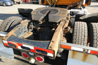 Rear view of a Freightliner CASCADIA 125 chassis showing a dirty fifth wheel and frame rails.