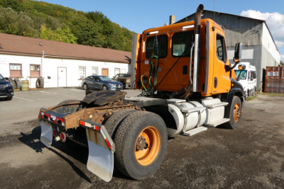 Orange Freightliner Cascadia 125 truck cab and chassis side view showing rear wheels and towing plate.