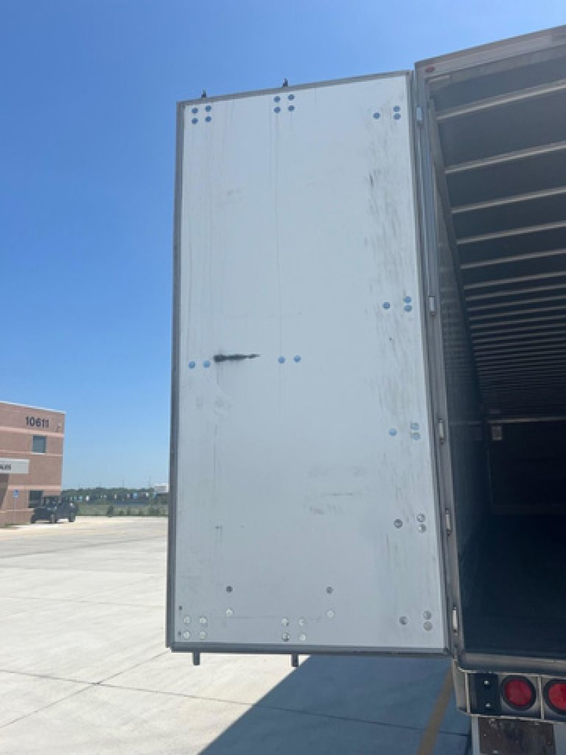 Trailer side door of a used 2012 utility van with exterior panels and rivets visible, loading ramp door open.
