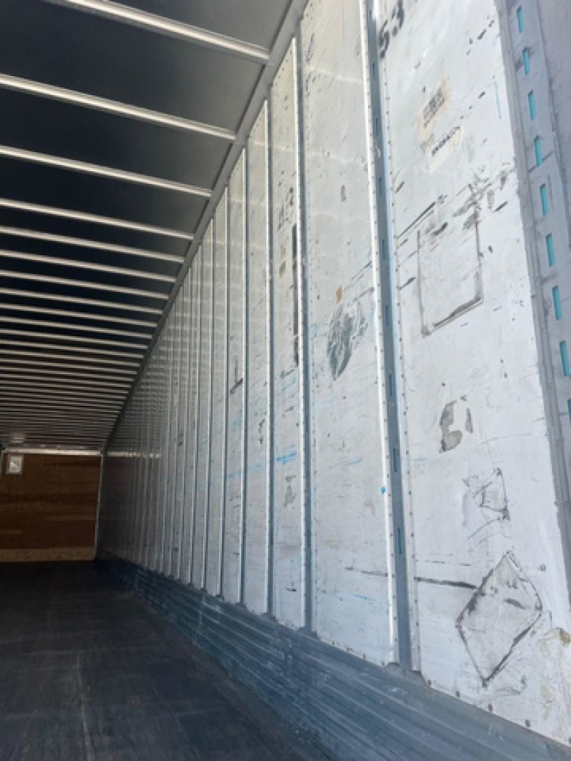 Trailer interior wall with metal panels and corrugated ceiling, empty cargo area, side wall panels with scuff marks.