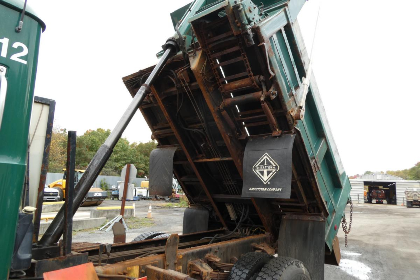 Dump truck bed tilted for unloading showing hydraulic cylinder and underside with Mack Granite insignia and chassis.