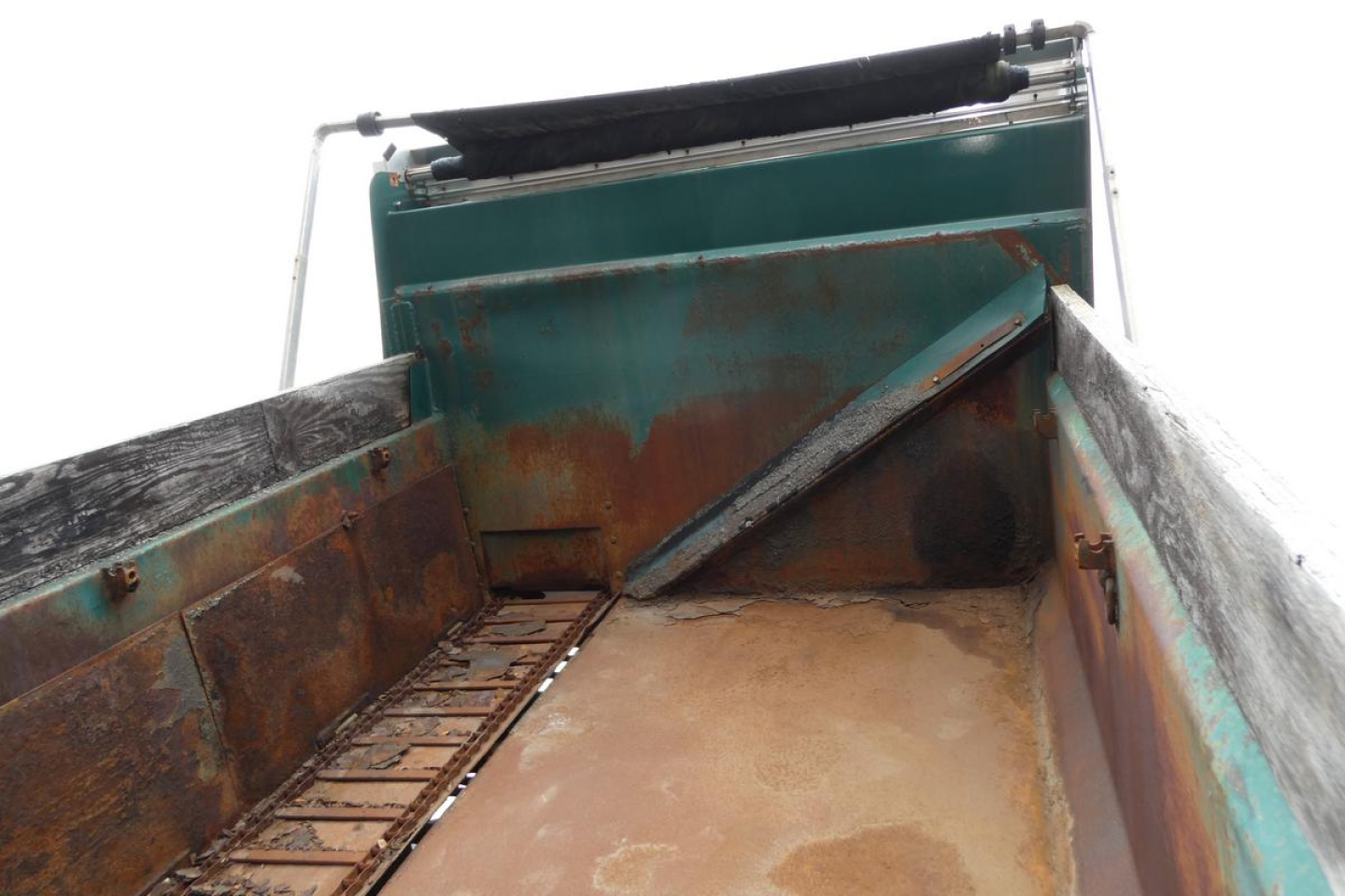 Dump truck bed of a 2010 Mack GU Granite GU712 showing rust on metal walls and empty bed with hydraulic structure at top.