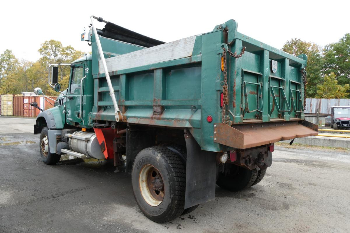 Dump truck bed and rear-view of a green Mack GU Granite GU712 dump truck with hydraulic hoist and rust-free metal tailgate line.
