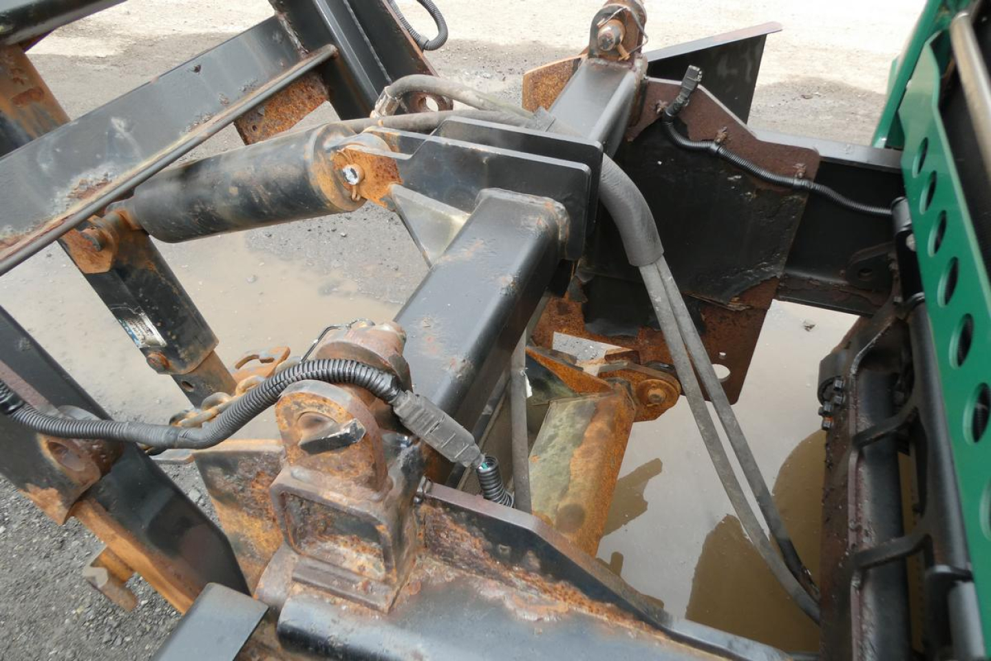 Mack GU (Granite) GU712 dump truck chassis close-up showing hydraulic lines, metal linkage, and rusted frame components.