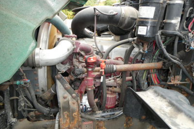 Mack GU dump truck engine bay showing radiator hoses, turbo, air intake, and various hoses and wiring around the engine.