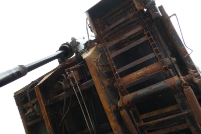 Mack GU Granite dump truck component showing hydraulic lift cylinder and rusted steel framework.