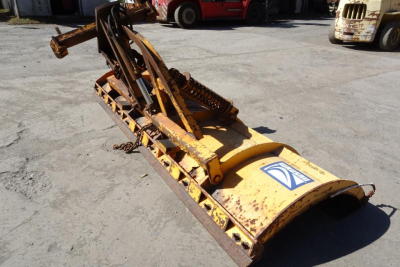 Front view of a yellow Mack GU Granite GU712 bucket attachment on a concrete lot, with rusted metal frame and hydraulic components.