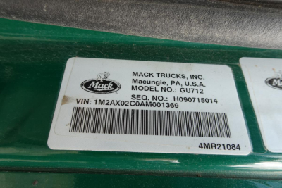 Mack Trucks label on dash area showing VIN: 1M2AX02CA ... unclear. Clear text includes MACK TRUCKS, INC., Macungie, PA, U.S.A., MODEL NO: GU712, SEQ. NO.: H09071501A, VIN: 1M2AX02C0AM001369, barcode, 4MR21084