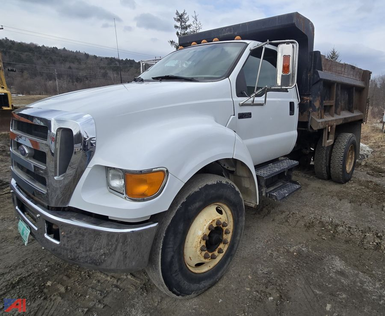 Dump truck 2004 Ford F750 in-service dump bed showing front grille, large headlights, amber turn signals, side step, dual rear wheels, and rusted dump body.