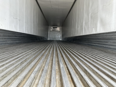 Trailer cargo area interior of a 2017 Utility 3000R flatbed trailer, showing corrugated floor rails and side walls, rear doorway at far end.