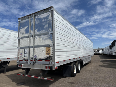 Utility 3000R trailer back view showing closed rear doors and dual-axle rear, aluminum body, warning stickers on doors, reflective striping along lower side.