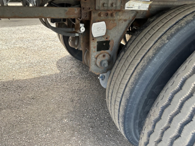 Trailer undercarriage showing suspension mount and dual tires of a 2017 Utility 3000R reefer trailer with rusted frame components and labeling plate visible.