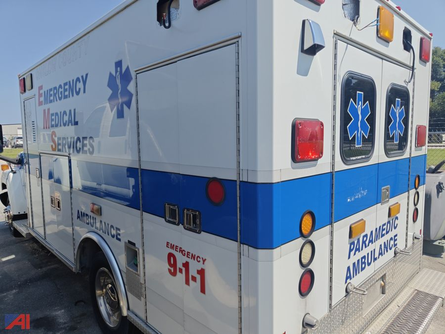 Ambulance side and rear showing Emergency Medical Services graphics and blue stripe on white body.