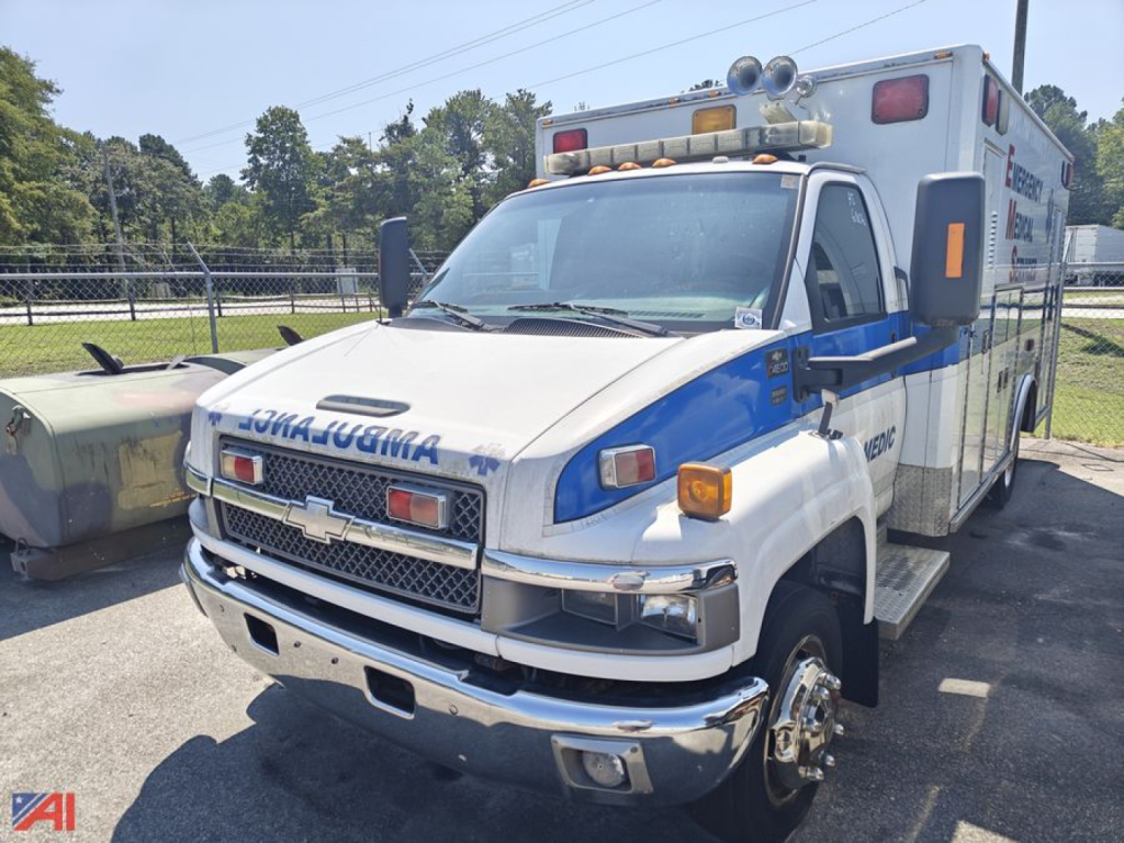 Ambulance truck front left angle showing Chevrolet C4500 with blue and white livery and emergency lights on cab roof.
