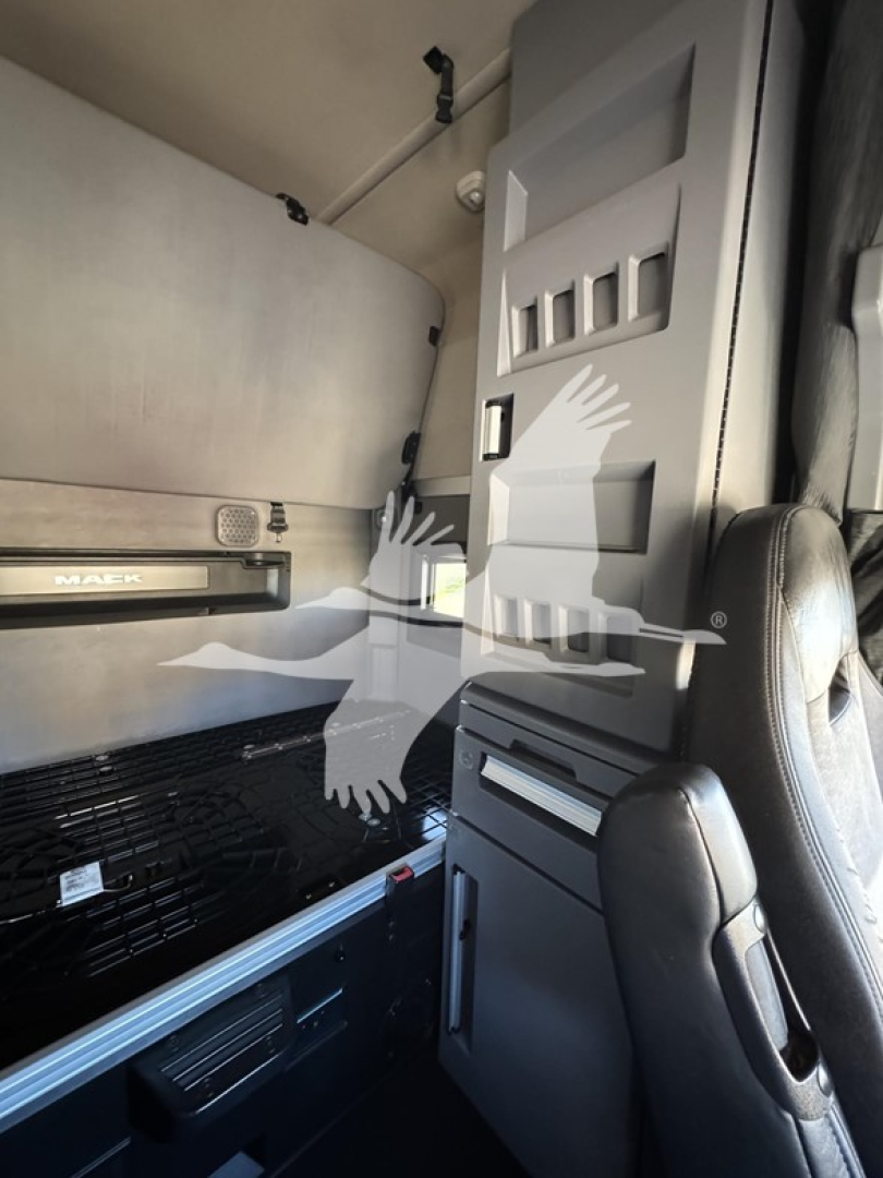 Cab interior of a 2019 Mack Anthem 64T showing sleeper area, cabinet with storage, control panel, and seat in view.
