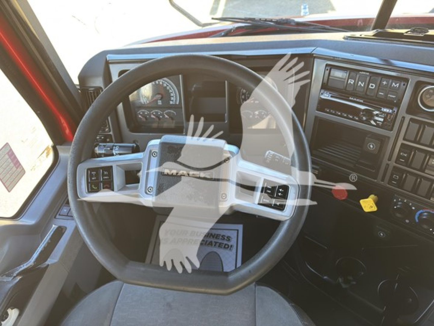 Mack Anthem truck dash and steering wheel interior showing steering wheel controls and dashboard gauges.
