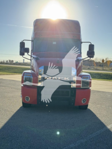 Truck front view of a red 2019 Mack Anthem 64T with large windshield, black grille, and side mirrors, daytime.