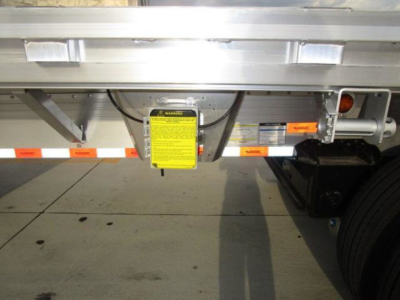 Trailer rear showing warning label and safety chain area on a flatbed trailer.