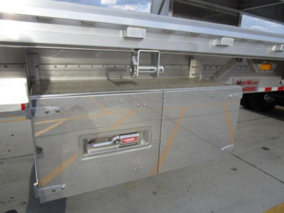 Flatbed trailer side compartment with latch handle and metal panels, underside with brackets and corner reinforcements. Some faint orange marking lines visible.