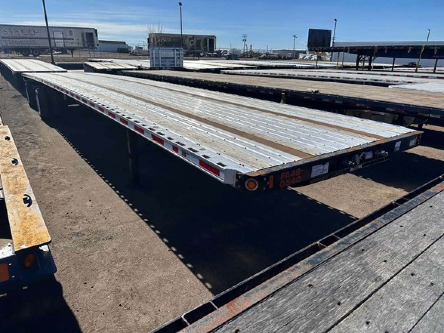 Flatbed trailer deck showing aluminum perforated surface with side rails and rear corner lights, 48' Fontaine Infinity combo flatbed in an outdoor lot.