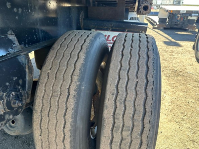 Flatbed trailer tires and undercarriage showing dual rear tires and frame of a Fontaine Infinity 48' combo trailer.