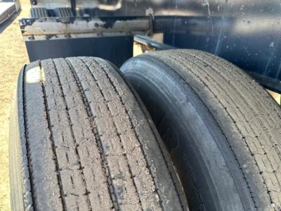 Dual trailer tires with treads and gravel on surface, undercarriage of Fontaine Infinity 48' combo flatbed visible.
