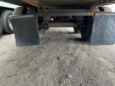 Trailer rear underside showing dual axles and mud flaps under the frame.