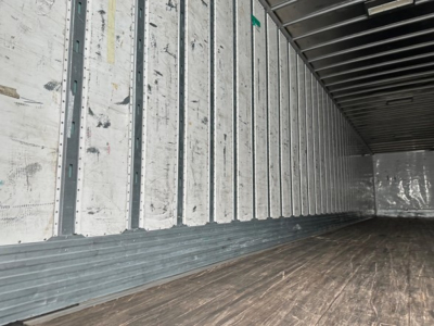 Trailer interior showing aluminum wall ribs and wooden floor; empty cargo space with metal sidewalls and ceiling ribs.