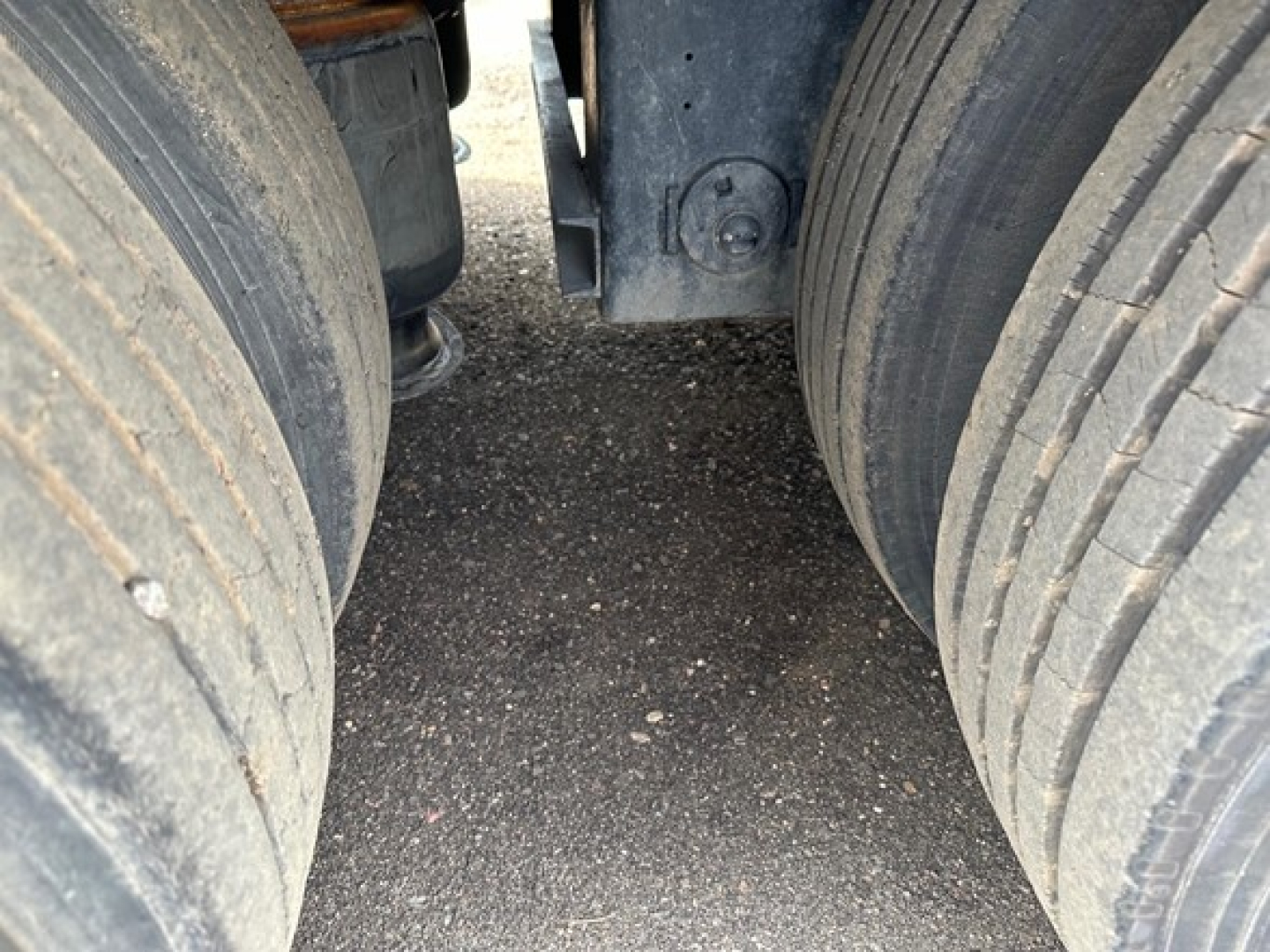 Twin rear tires and undercarriage of a trailer showing dual wheel assemblies and frame clearance. 