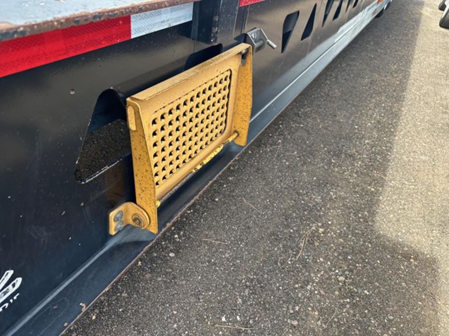 Trailer side view showcasing a yellow grated access panel near the undercarriage of a 40 Ton hydraulic tail trailer. Visible details include perforated guard and mounting brackets.