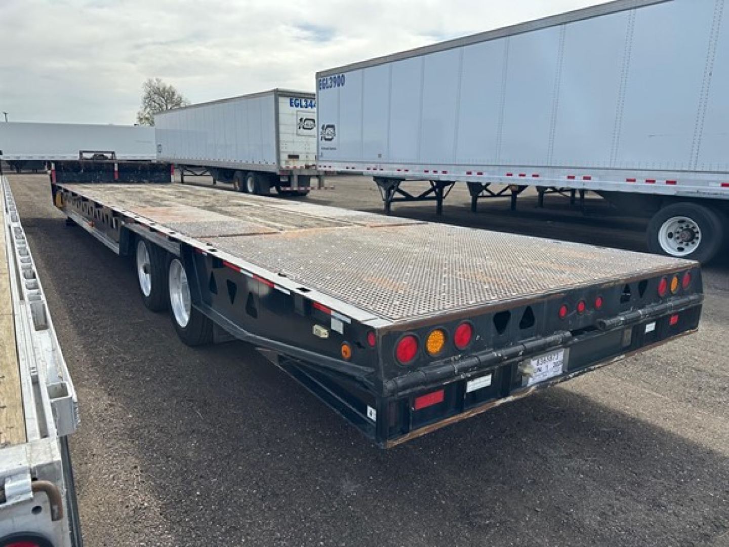 Trailer showing 40 ton hydraulic tail trailer with flatbed and dual rear axles, rear lights and metal deck.