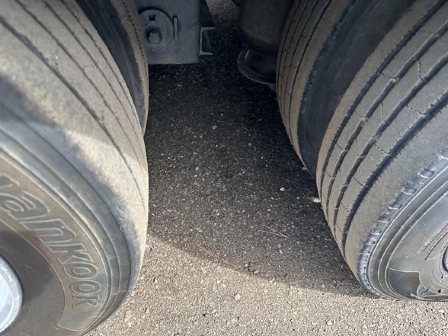 Two large trailer tires with tread visible; gap between tires and undercarriage components partially seen.