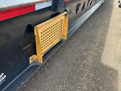 Trailer side view showcasing a yellow grated access panel near the undercarriage of a 40 Ton hydraulic tail trailer. Visible details include perforated guard and mounting brackets.