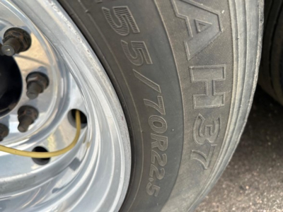 Tire sidewall with '255/70R22.5' marking and wheel visible on a trailer.