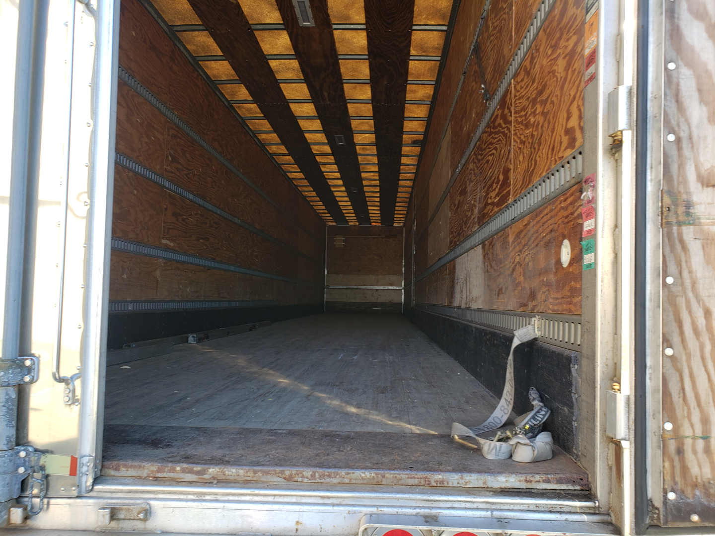Trailer interior of a 53' dry van showing wooden sidewalls and empty cargo floor with tie-down rails along the walls.