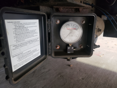 Calibration label with instructions and a round gauge labeled ‘Weight’ and ‘lbs’ on a Great Dane 53' dry van trailer. Gauge shows numbers around 0-100 with a needle at 0. On the left, a hinged door with a printed notice containing m