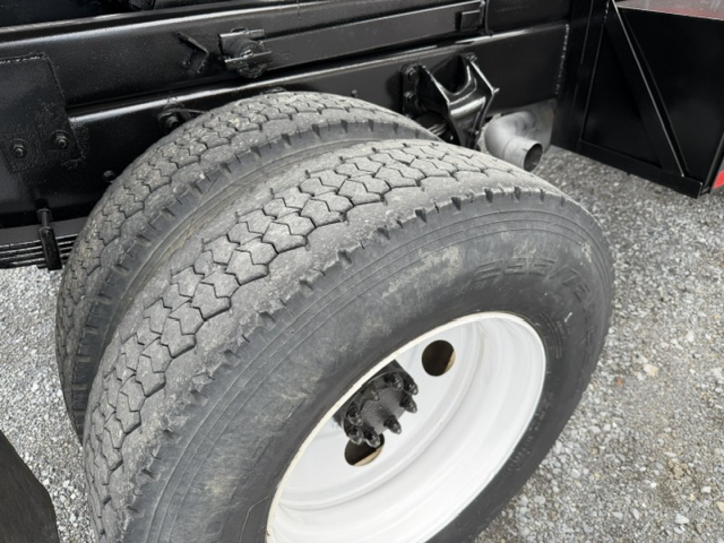 Dual rear tires on a Ford F-750 SD dump truck chassis with white steel wheel and black frame visible.
