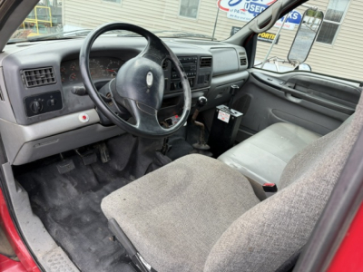 Cab interior of a 2006 Ford F750 SD dump truck showing steering wheel, dashboard, driver seat, and center console with gear shifter.