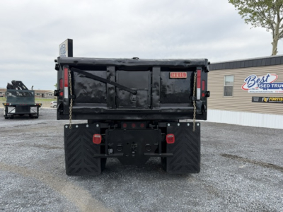 Rear view of a black Ford F750 SD dump truck with dual rear tires and tailgate chains visible, Parking lot behind.