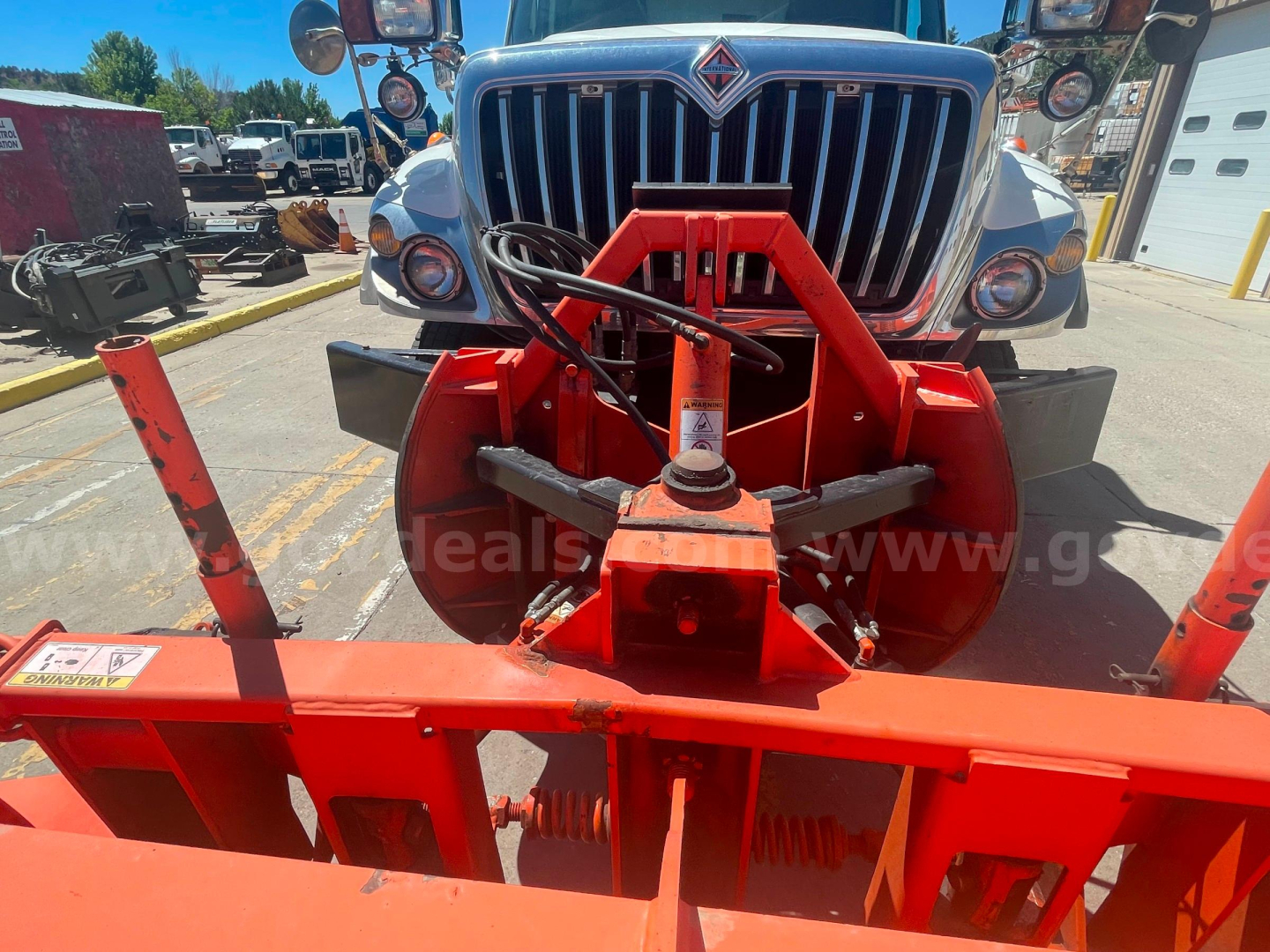 Front view of a 2012 International 7400 dump truck with a red dump body attachment and chrome grille in a dealership lot.