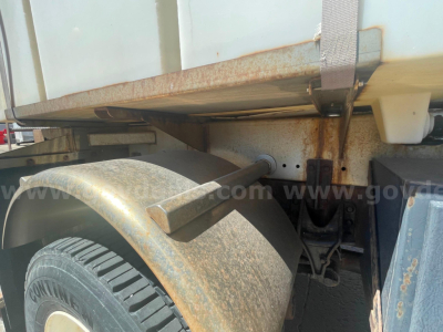 Truck rear wheel well and undercarriage showing rust, fender, tire, and hitch area from a 2012 International 7400 dump truck.