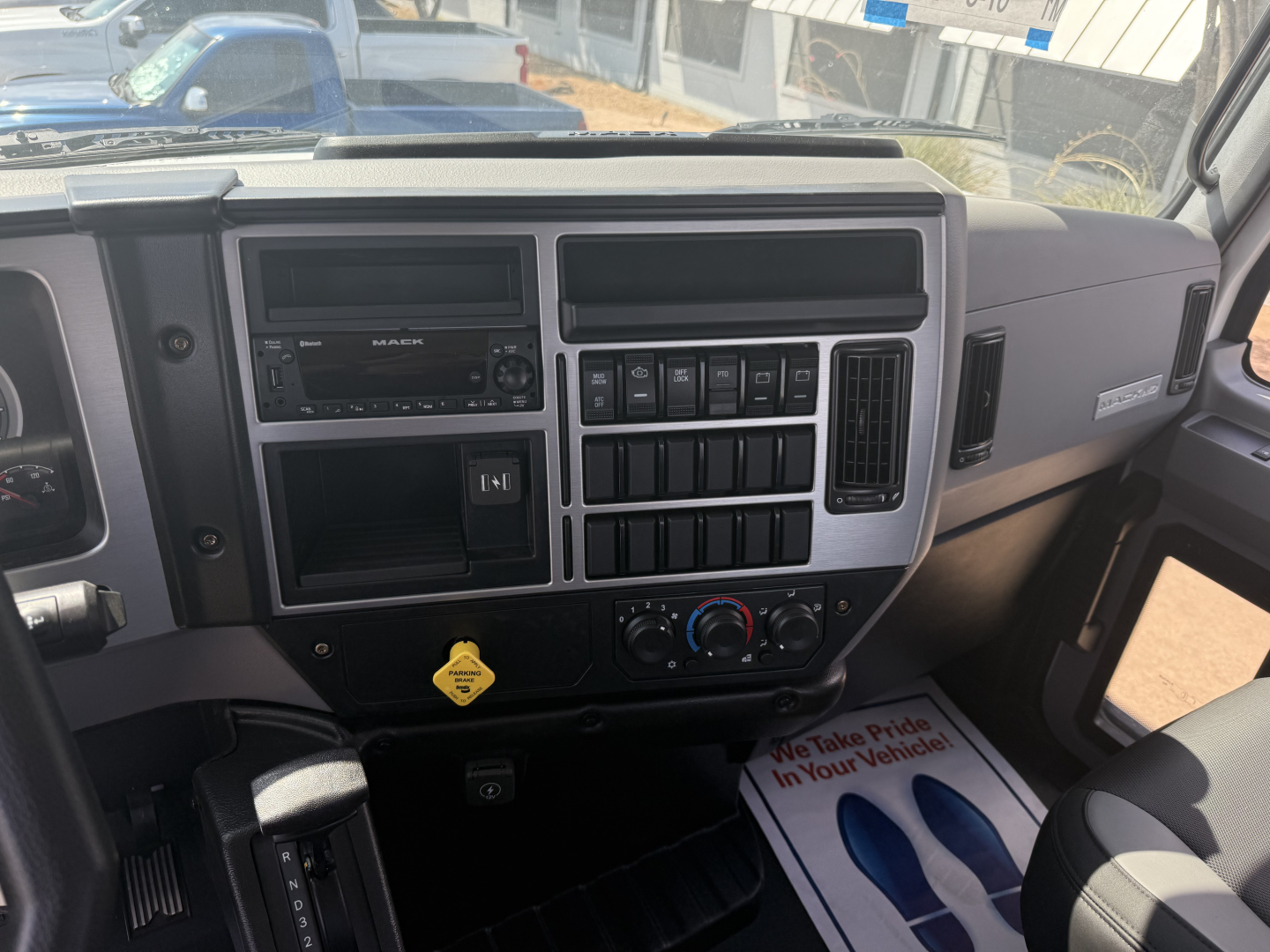 Dashboard of a 2026 Mack MD6 truck cab showing instrument panel, controls, climate dials, radio, and cup holder area.