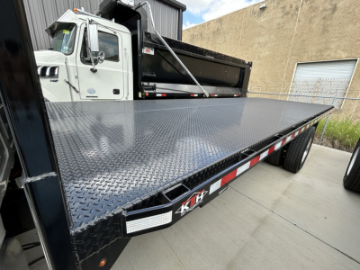 Flatbed truck deck with diamond plate showing 6x truck bed and reflective safety markings.