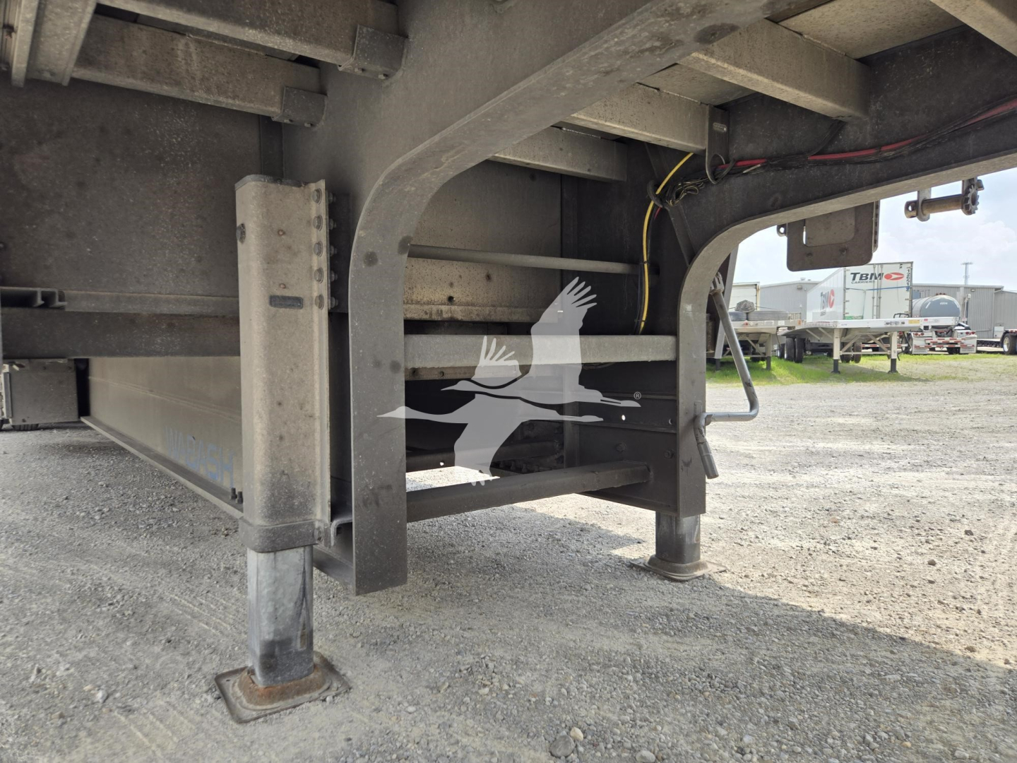 Understructure of a used 2024 Wabash drop deck trailer showing stabilizer leg, frame, and side rail with some wiring; no legible model numbers visible.