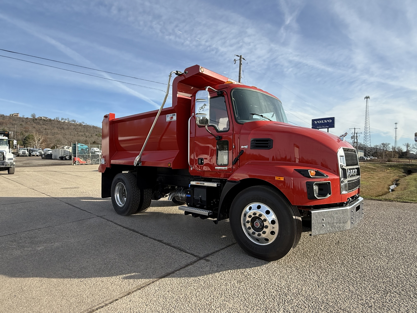Truck: red 2025 Mack MD7 dump truck in side view showing cab, dump bed, and large mirrors.