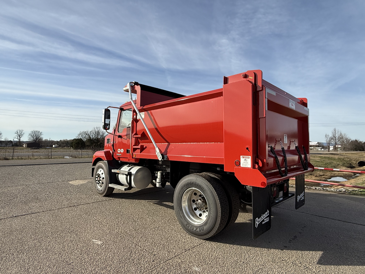 MD7 dump truck side and rear showing red dump bed, dual rear wheels, and side mirrors.