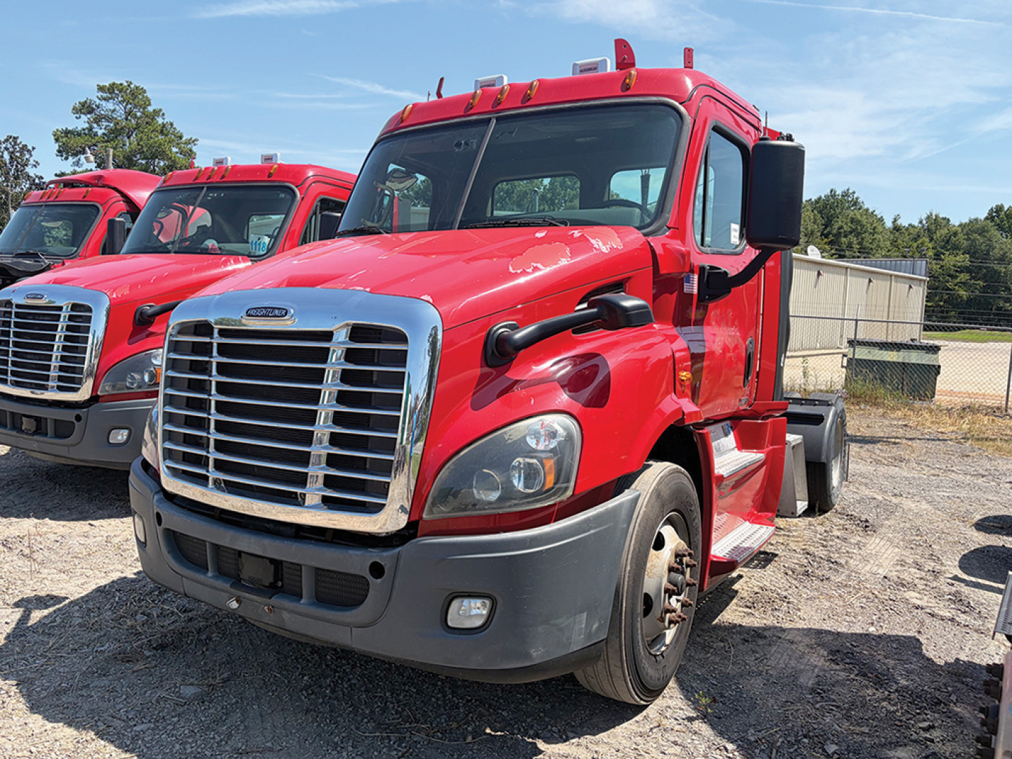 Freightliner Cascadia Evolution 2018 semi-truck cab in red, front grille view with other red trucks in background.