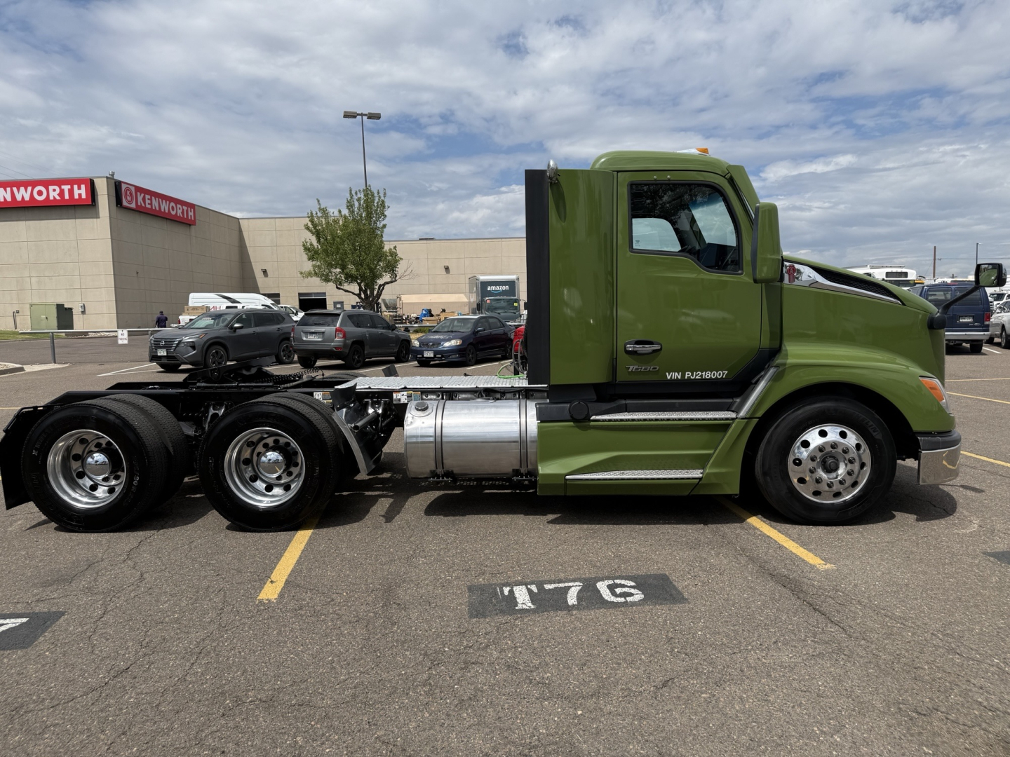 Kenworth T680 truck side view with bright green cab and chassis, showing wheels, fuel tanks, and exhaust area.