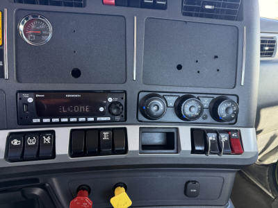 Kenworth T680 dash panel showing center console with climate controls, radio, and switch panels; left gauge cluster visible with 'WELCOME' display, multiple switches and knobs.