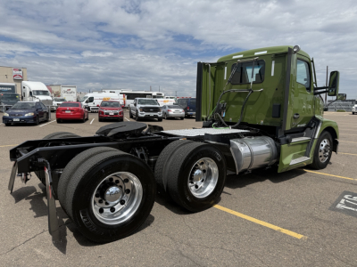 Green Kenworth T680 side view showing chassis and cab with dual rear axles and fuel tanks.